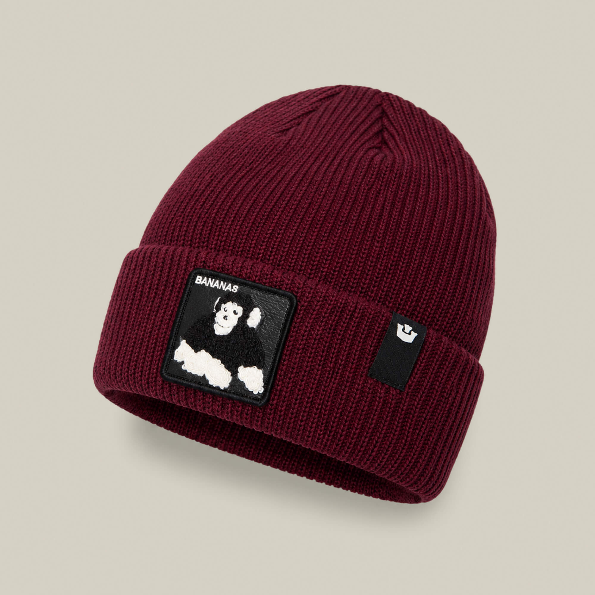 The Double Stuffed - Bananas Beanie by Goorin Bros. is crafted in a rich burgundy rib knit and features a warm, cuffed design with a folded brim, a black-and-white monkey patch, and a small black tag with the white Goorin Bros. logo.