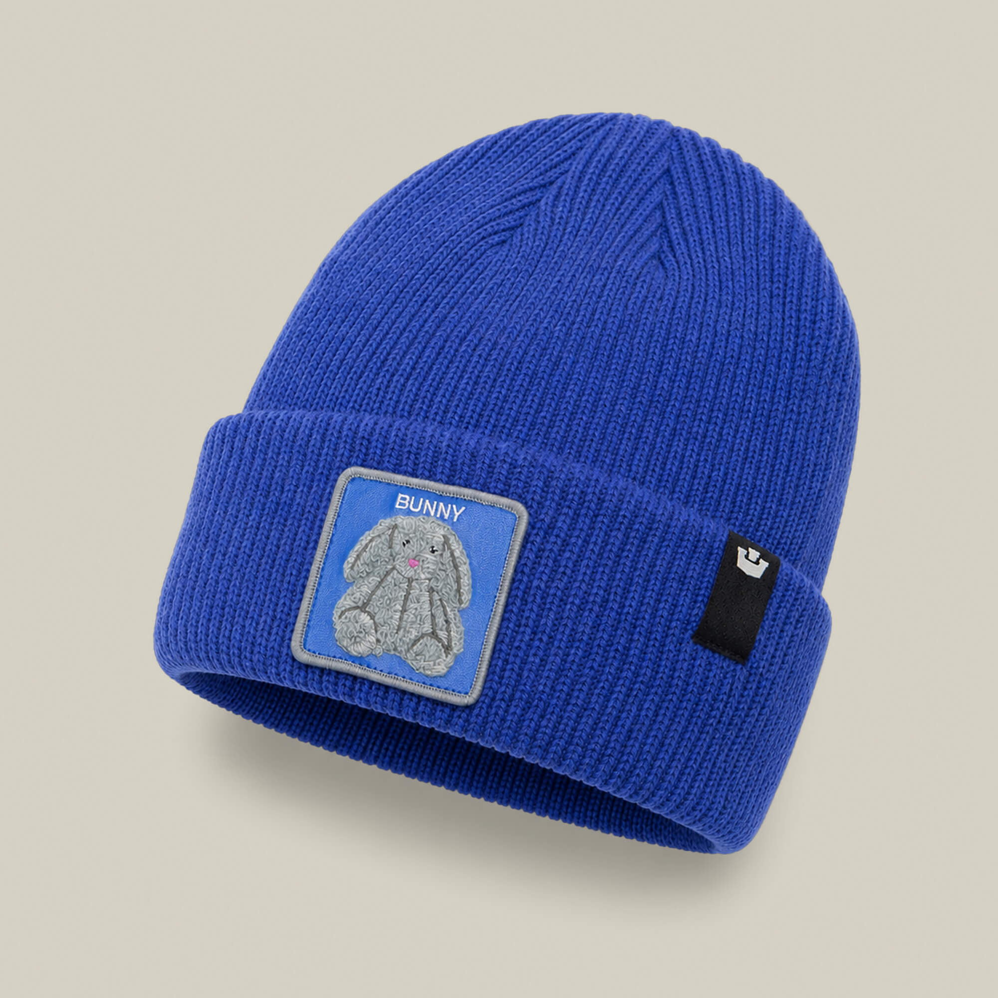 The Double Stuffed - Bunny Beanie by Goorin Bros. is a blue knit hat with a folded rib-knit cuff, featuring a patch with a gray bunny and the word “BUNNY,” along with a small black Goorin Bros. tag.