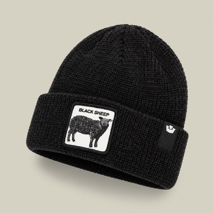 The Black Sheep Beanie by Goorin Bros is a black ribbed knit beanie with a white graphic patch featuring a black sheep illustration and text on the front, displayed against a neutral background.