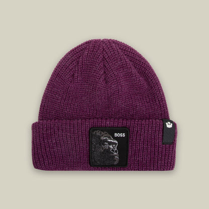 The Boss Beanie by Goorin Bros is a purple ribbed knit beanie featuring a black square patch with a gorilla illustration and "BOSS" text on the front, displayed flat against a neutral background.