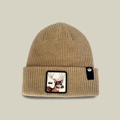 The Bae Beanie from Goorin Bros. is an everyday knit in a chalk hue, crafted from soft acrylic, and features a patch with a deer head and the word “BAE,” along with a small black tag on the cuff.