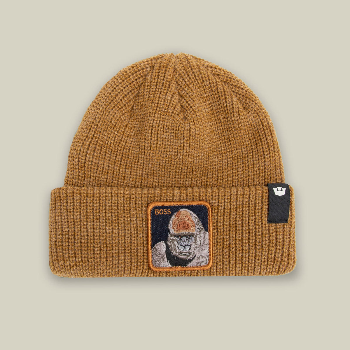The Boss G Beanie by Goorin Bros. is a camel-colored ribbed knit beanie with an embroidered patch featuring a gorilla face and "BOSS" text on the front, displayed against a neutral studio background.