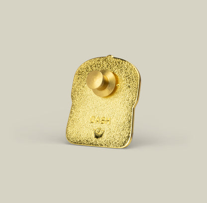 The Goorin Bros. Cash Cow Trucker Pin is a gold-colored zinc alloy bread slice with a textured finish, button backing, and “CASH” engraved on it.