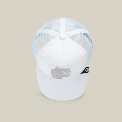 The Goorin Bros. Lil Pantherino is a white mesh trucker hat with a bear patch on the front and a small black side tag, shown against a beige background.