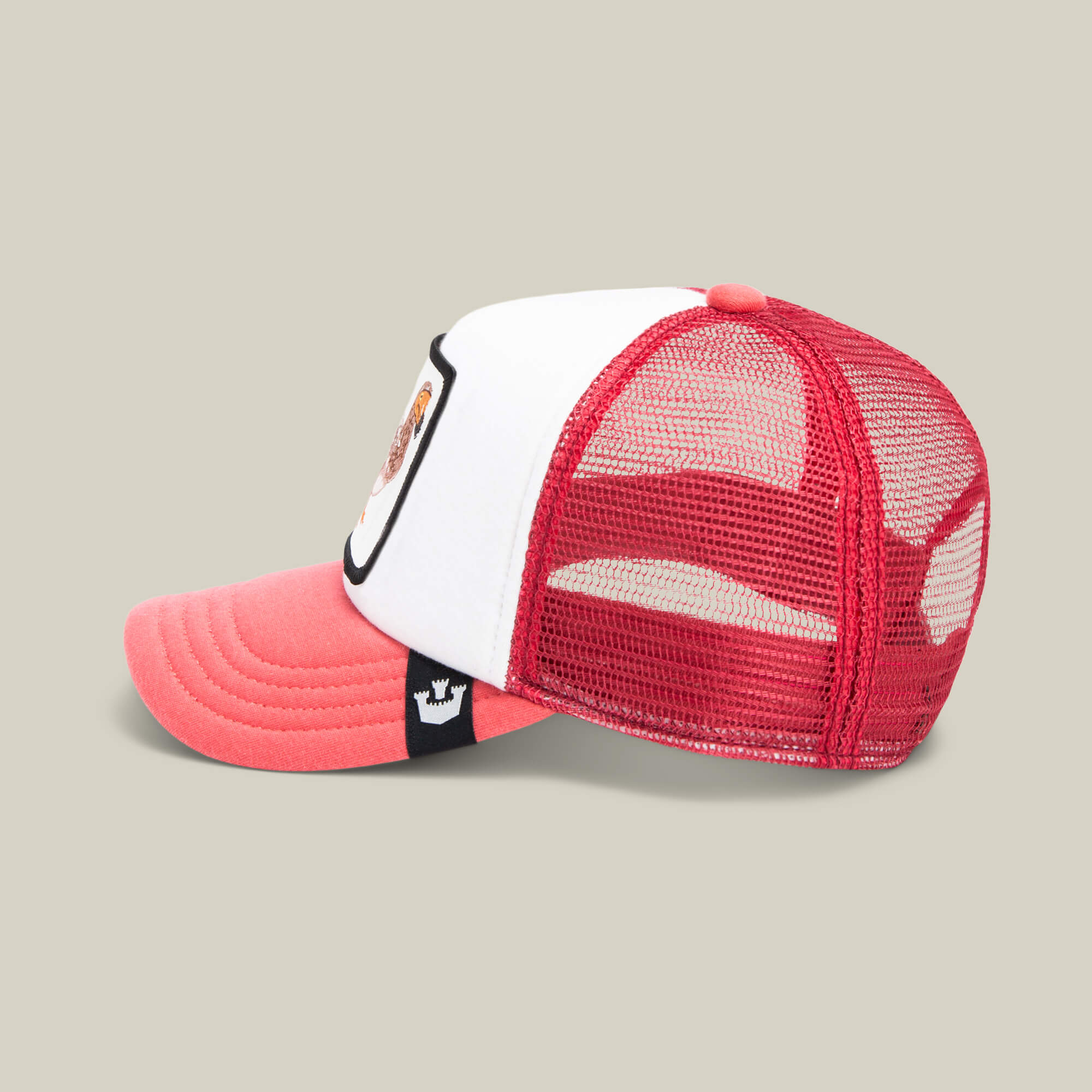 A side view of the Goorin Bros. Dodo Kiddo cap for kids, featuring a red and white mesh design, curved red brim, mesh back, and a black tag with a white crown logo—ideal as the perfect kids' cap.