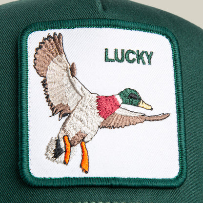 A close-up of The Lucky Duck Mini by Goorin Bros.—a kid-sized green crown cap with a white flying duck patch and "LUCKY" embroidered in green.