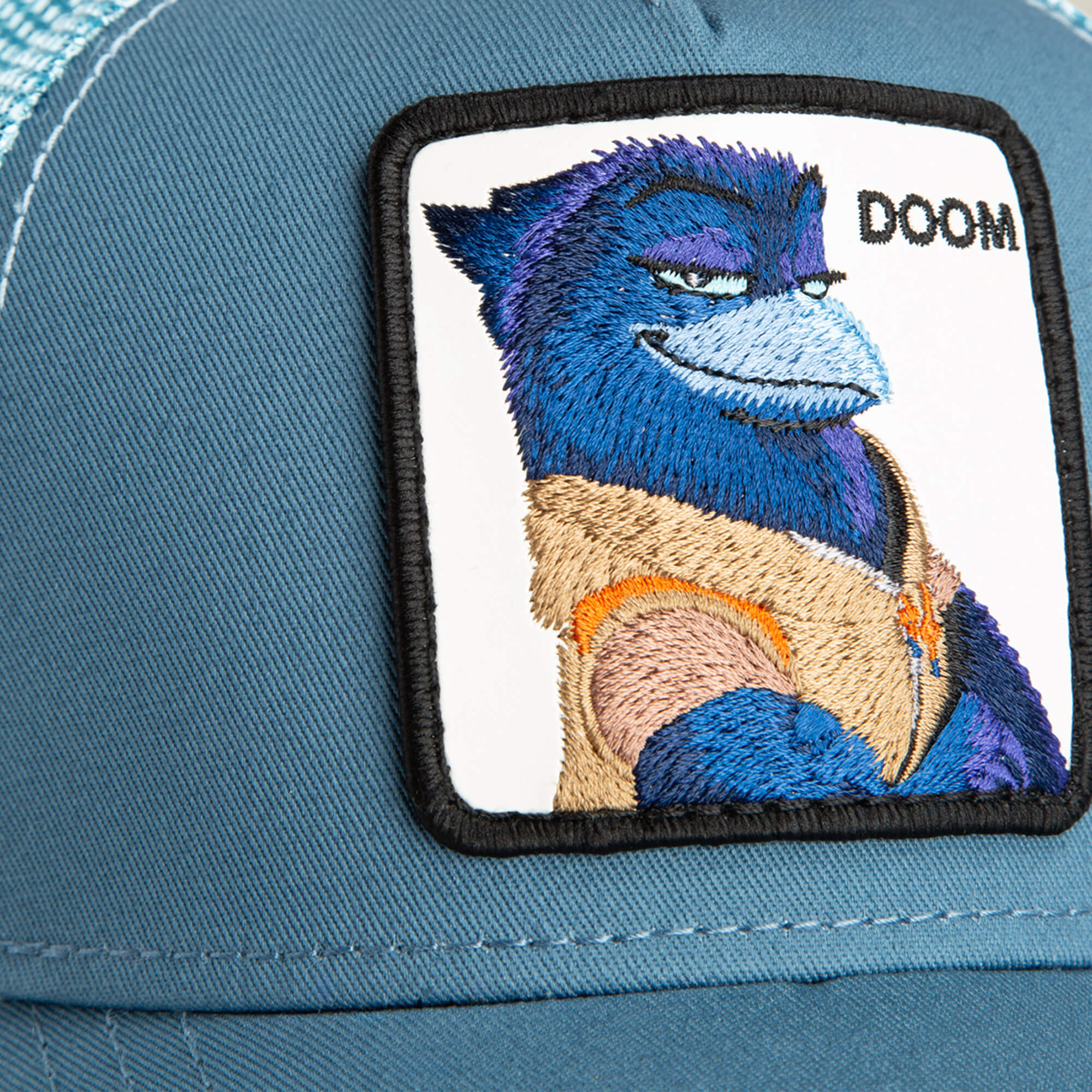 Close-up of the Goorin Bros. BG2 - Doom (KIDS) cap, featuring a blue fabric with an embroidered patch of a smirking blue and purple animal and "DOOM" text—perfect for adding playful aviator style to any kid's look.