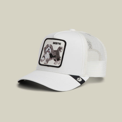 The Goorin Bros. Bestie Trucker Mini is a white mesh trucker cap with a black brim stripe, featuring an embroidered dog patch on the front panel labeled "Bestie," displayed on a neutral background.