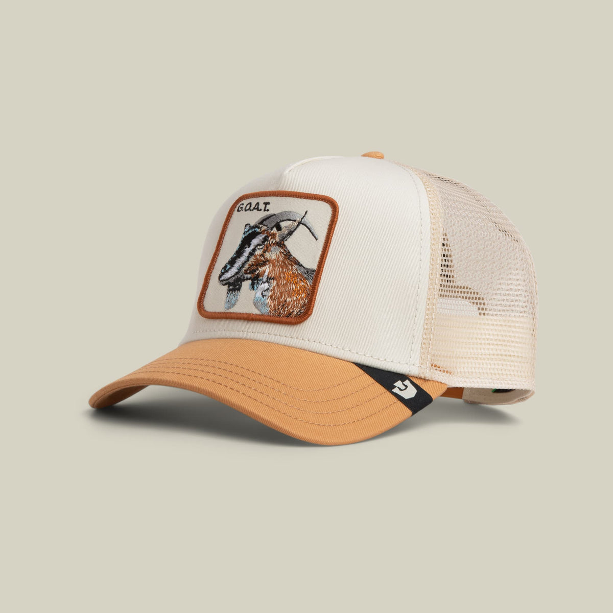 The Goorin Bros. Goat Trucker Mini features a white cotton front panel and cream mesh back with an embroidered goat patch in tan and brown, orange trim, and an adjustable snapback closure, displayed against a neutral background.
