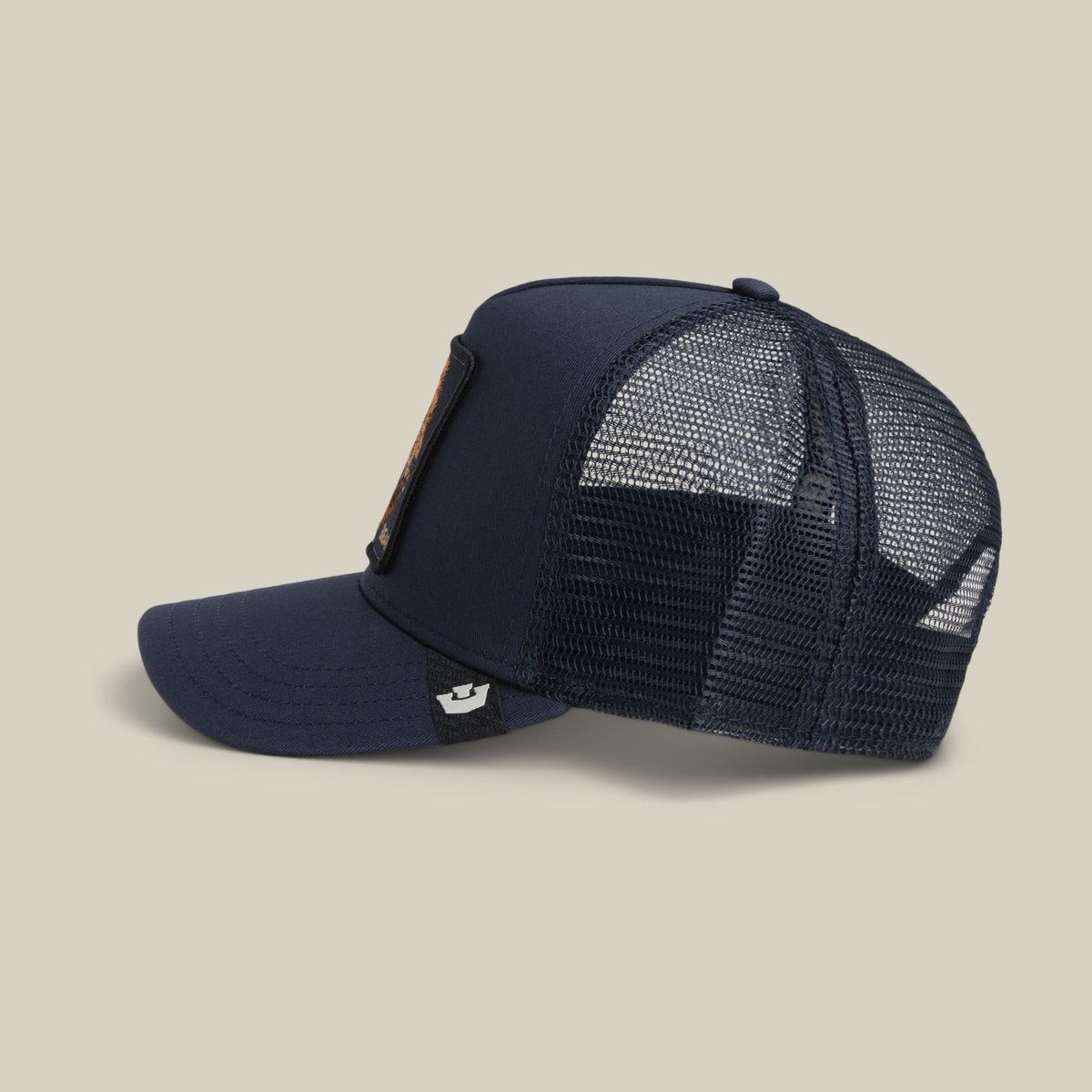 The Goorin Bros. Bear Trucker Mini is a navy blue mesh trucker hat with a solid front panel and breathable mesh back, featuring a small embroidered patch on the side and snapback closure, displayed against a neutral studio background.