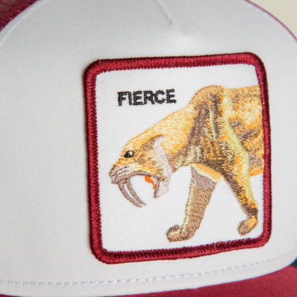 The Goorin Bros. Fierce Saber-tooth Tiger Mini trucker hat features a red and white color block design with an embroidered patch of a saber-tooth tiger with bared fangs on the front panel, shown flat lay on a white background.