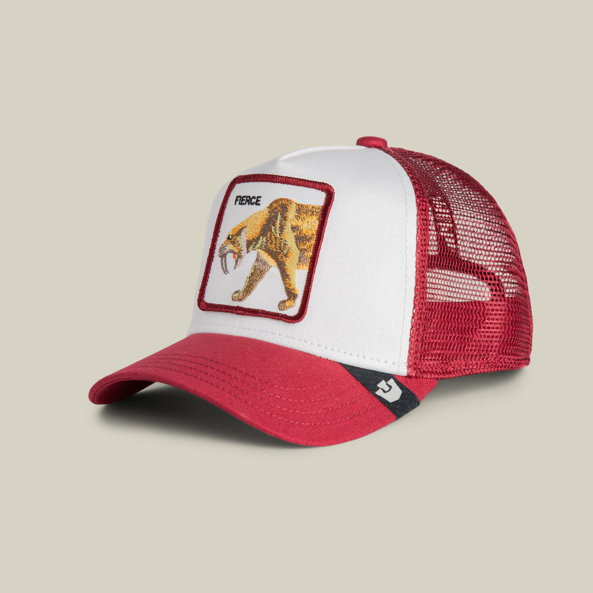The Goorin Bros. Fierce Saber-tooth Tiger Mini trucker hat features a white front panel with a burgundy-bordered embroidered saber-tooth tiger patch labeled "Fierce," burgundy mesh back panels, and a red bill with black stripe detail, displayed against a neutral background.
