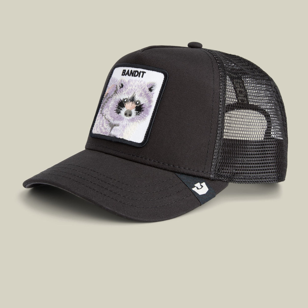 The Goorin Bros. Bandit Trucker Mini is a black mesh trucker cap featuring a white patch on the front with a raccoon graphic and "Bandit" text, displayed on a neutral beige background.