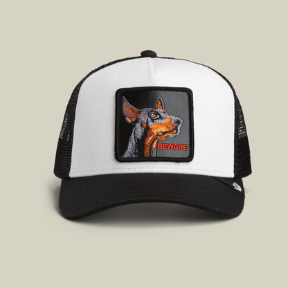 Goorin Bros. Beware Trucker Mini in Dust/Void features a black and white design with an embroidered patch depicting a Doberman’s head and the word “Beware” in bold red text.