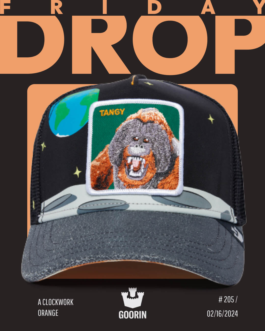 A black mesh Goorin trucker hat featuring an embroidered orangutan patch labeled TANGY, with Earth and stars in the background. Text reads FRIDAY DROP and A CLOCKWORK ORANGE. American made quality you can trust.
