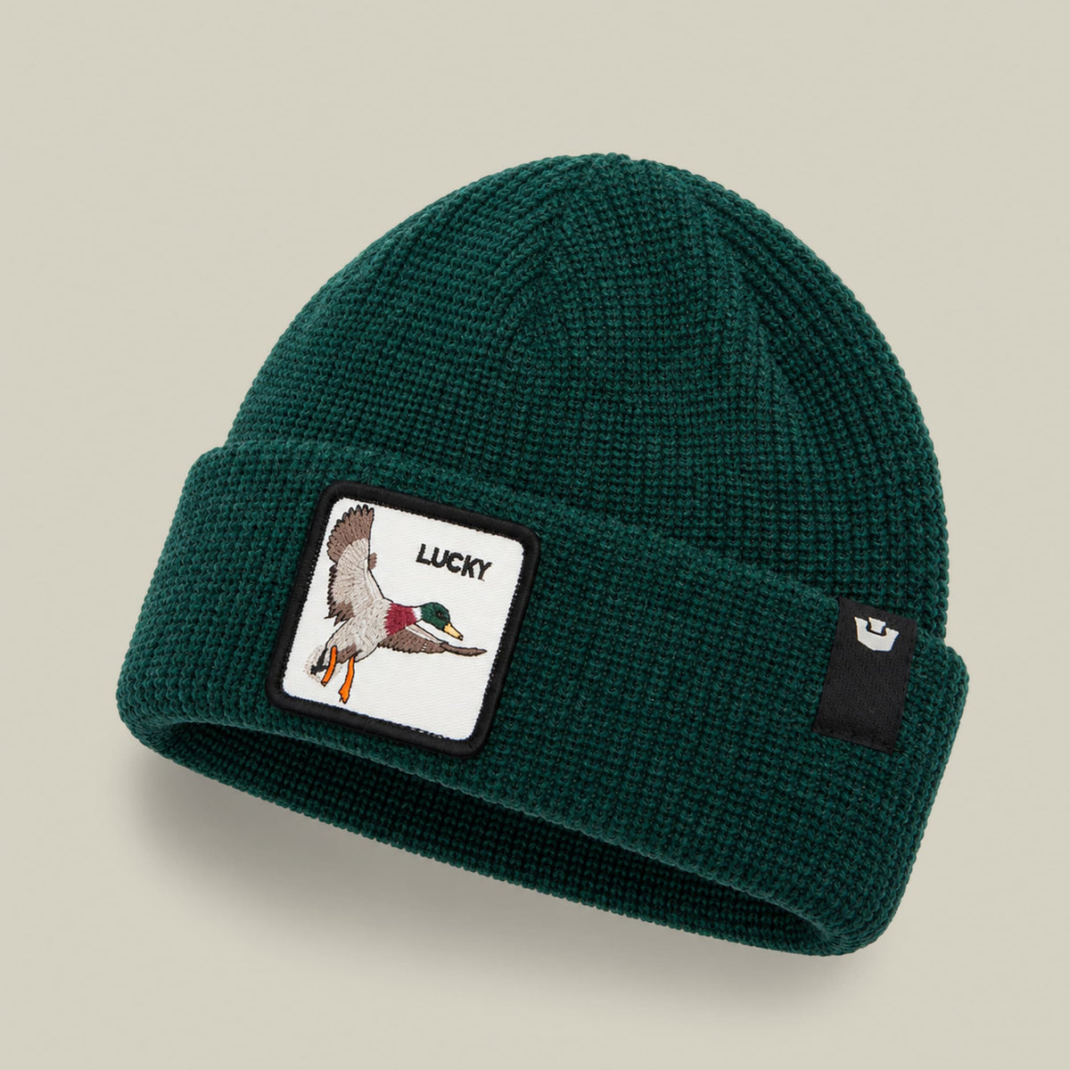 The Lucky Beanie Mini by Goorin Bros. is a teal green ribbed knit beanie featuring a embroidered duck patch with "Lucky" text on the front and a small brand patch on the side, displayed on a neutral studio background.