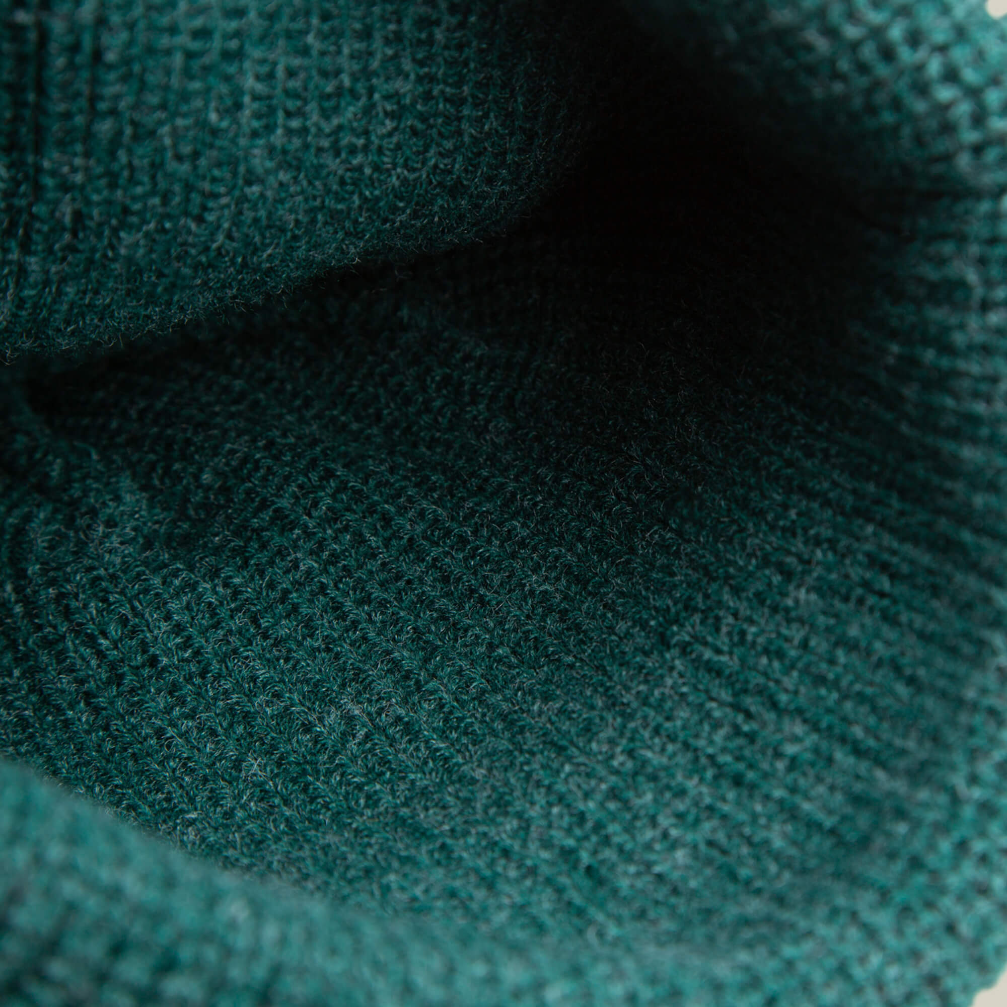 Close-up view of the inside of The Playful Beanie Mini by Goorin Bros., showing cozy green knit fabric and detailed stitching.