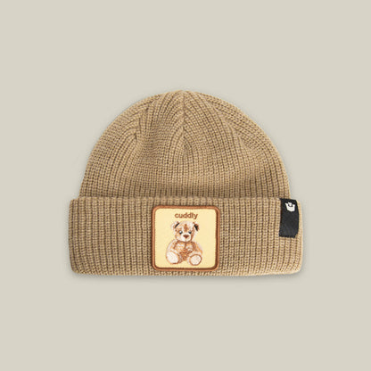 The Cuddly Beanie Mini by Goorin Bros. is a tan kids’ knit beanie with a folded brim, a teddy bear patch reading "cuddly," and a small black side tag.