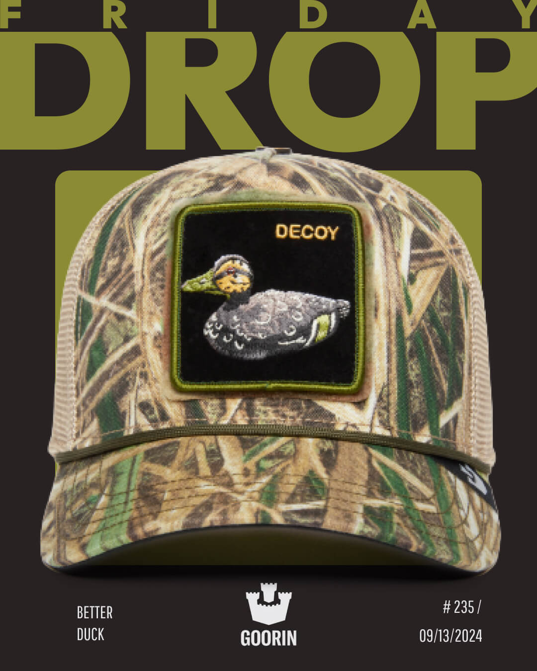 A camouflage trucker hat with a patch of a duck labeled “DECOY,” displayed on a dark background with FRIDAY DROP text above. Known for bold hat designs, Goorin branding and release info are shown below.