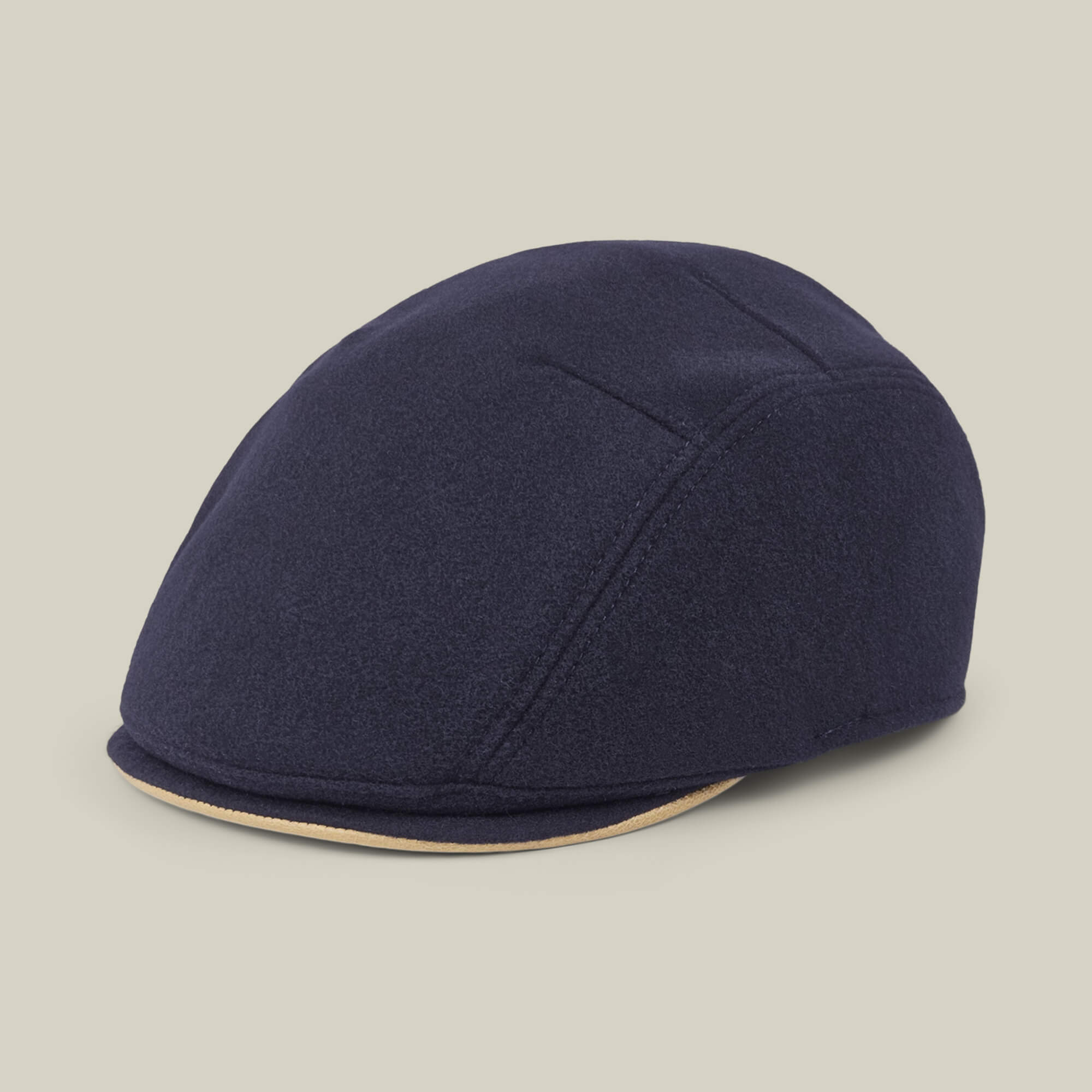 The “Cornerstone” flat cap by Goorin Bros., handmade in New Jersey, features visible stitching and a beige trim along the brim, showcased on a neutral background.