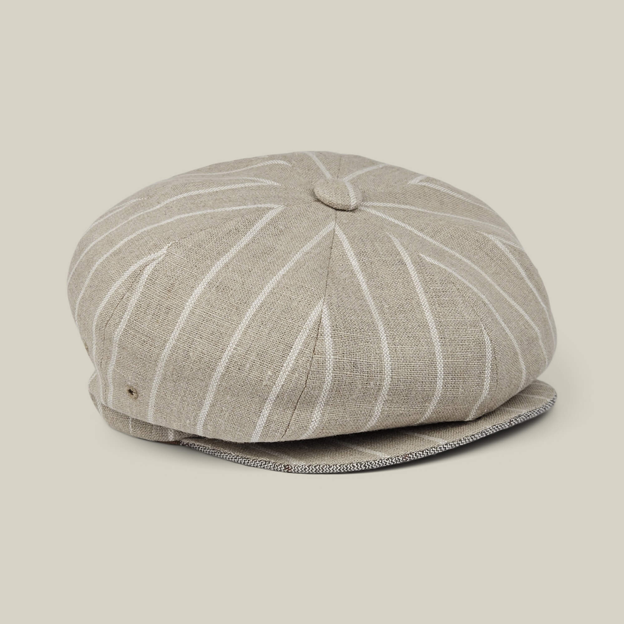 Rincon Park by Goorin Bros. is a beige linen blend newsboy cap featuring white vertical pinstripes and a button detail on top, hand cut and sewn for a classic Gatsby silhouette, displayed on a neutral background.