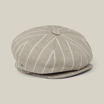 Rincon Park by Goorin Bros. is a beige linen blend newsboy cap featuring white vertical pinstripes and a button detail on top, hand cut and sewn for a classic Gatsby silhouette, displayed on a neutral background.