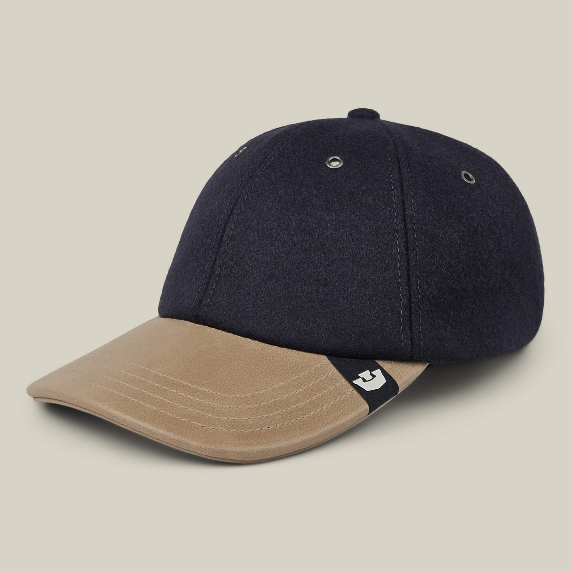 The Bixby by Goorin Bros. is a handmade two-tone baseball cap from New Jersey, showcasing a dark navy crown, beige suede brim, metal eyelets, and a small black and white logo tag on the side of the brim.