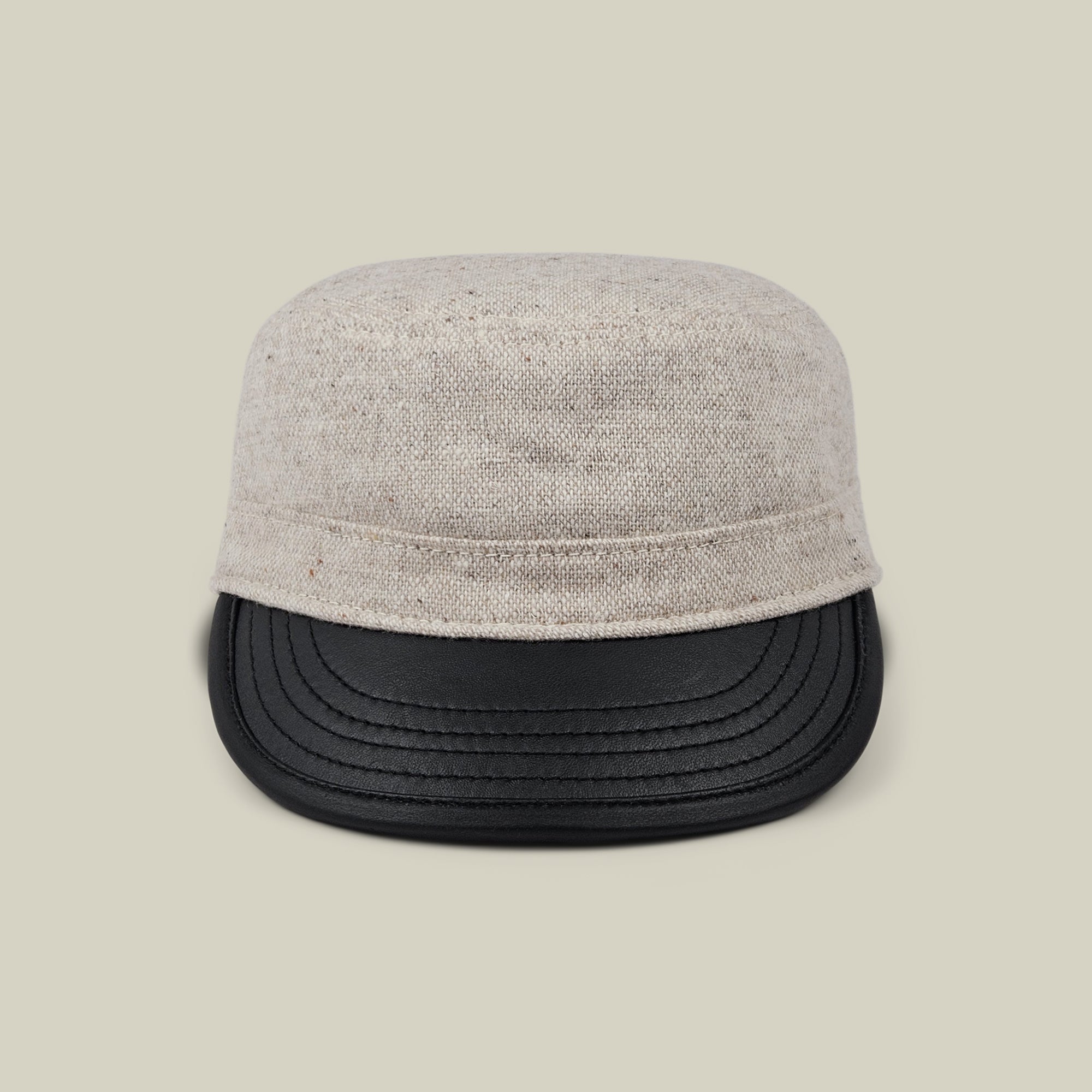 Front view of the Goorin Bros. South Boulder cadet cap, featuring a heritage-inspired design with a light beige wool crown and black faux leather bill, hand cut and sewn in the USA, displayed against a plain beige background.