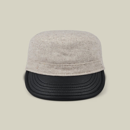 Front view of the Goorin Bros. South Boulder cadet cap, featuring a heritage-inspired design with a light beige wool crown and black faux leather bill, hand cut and sewn in the USA, displayed against a plain beige background.