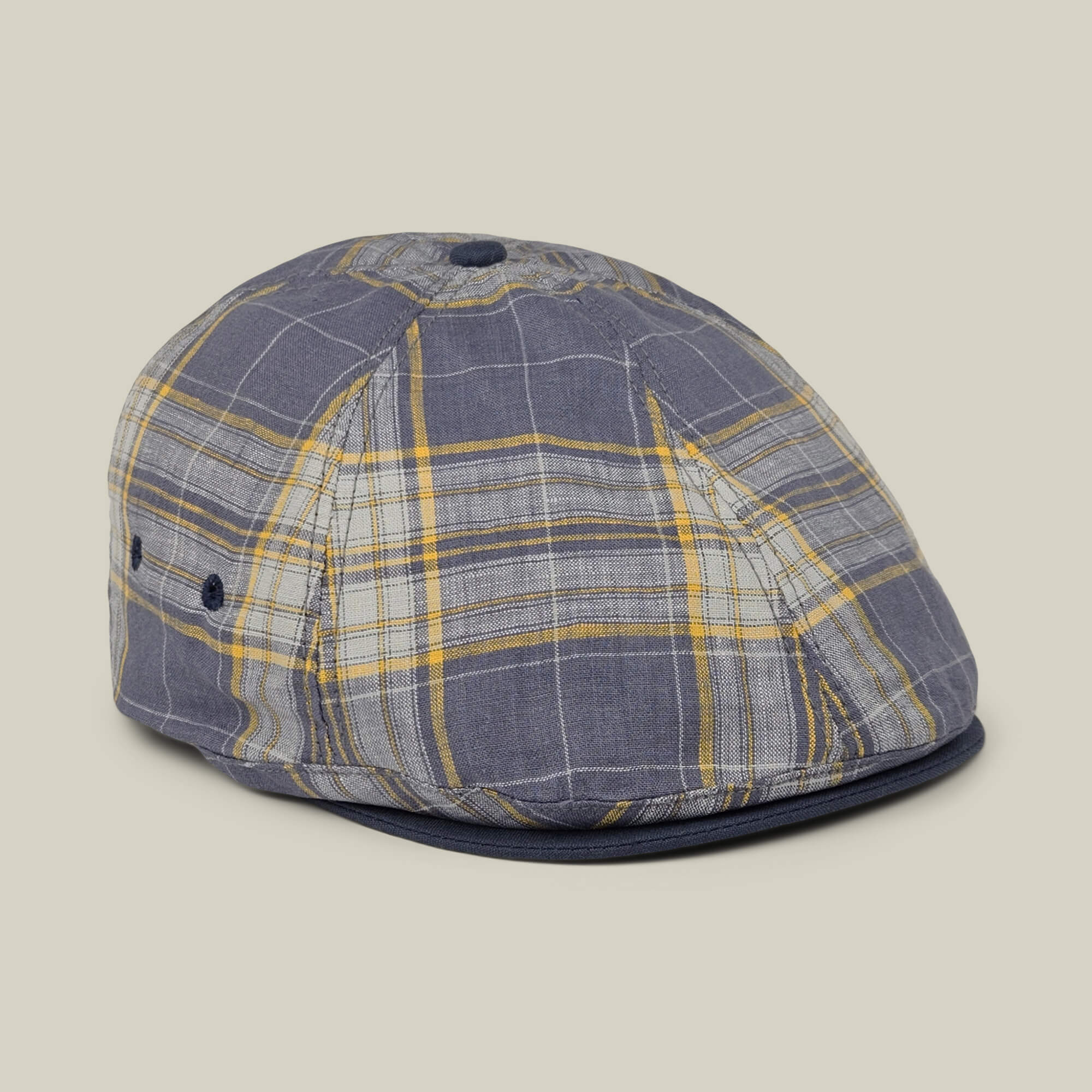 Point Lobos by Goorin Bros. is a blue and yellow plaid 6-panel Ivy flat cap, handmade in the USA from a breathable cotton blend. It features a button on top, ventilation eyelets on the side, and a short brim, showcased against a neutral background.