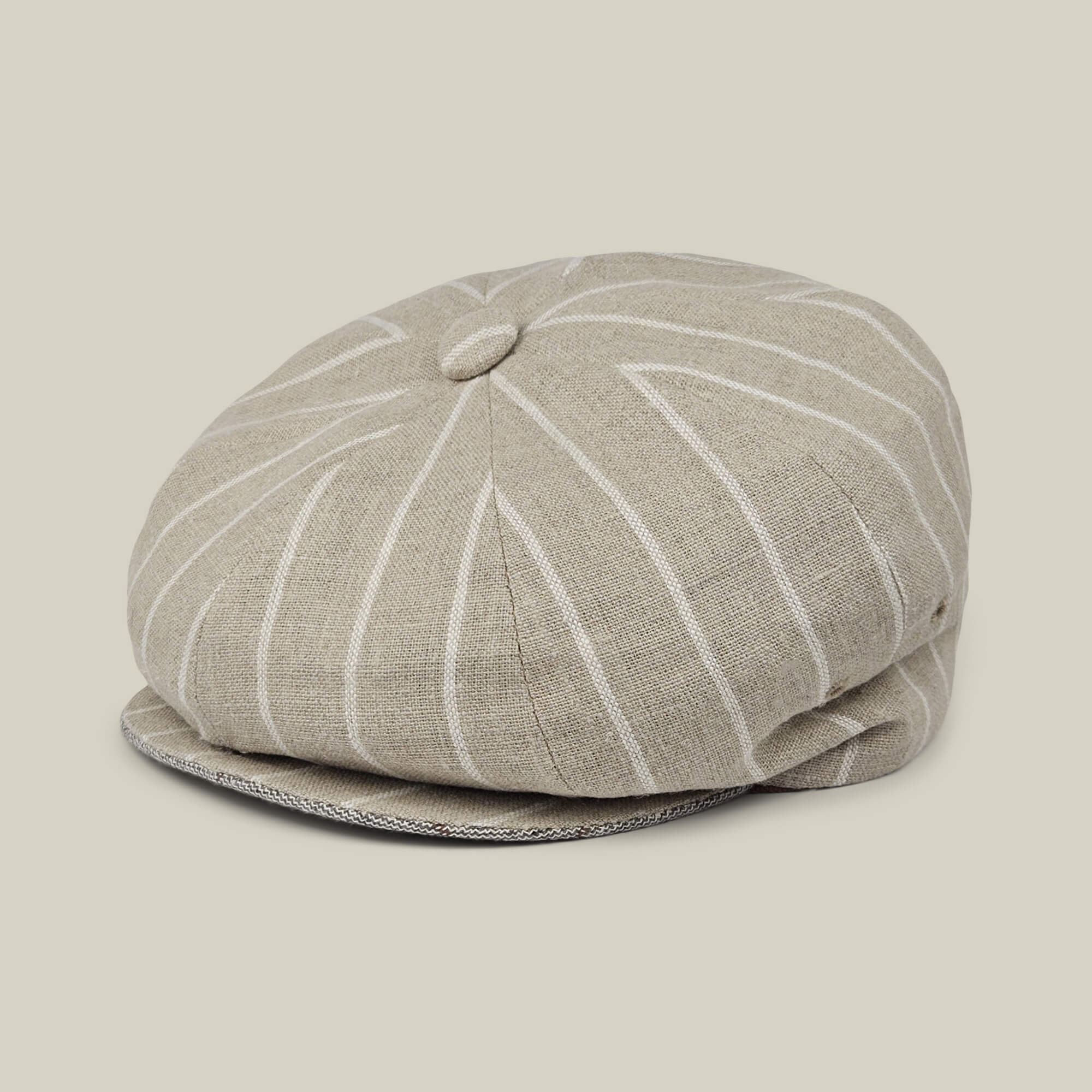 The Rincon Park newsboy cap by Goorin Bros. features a beige linen blend with white pinstripes, a top button, and a classic Gatsby silhouette, displayed on a neutral background.