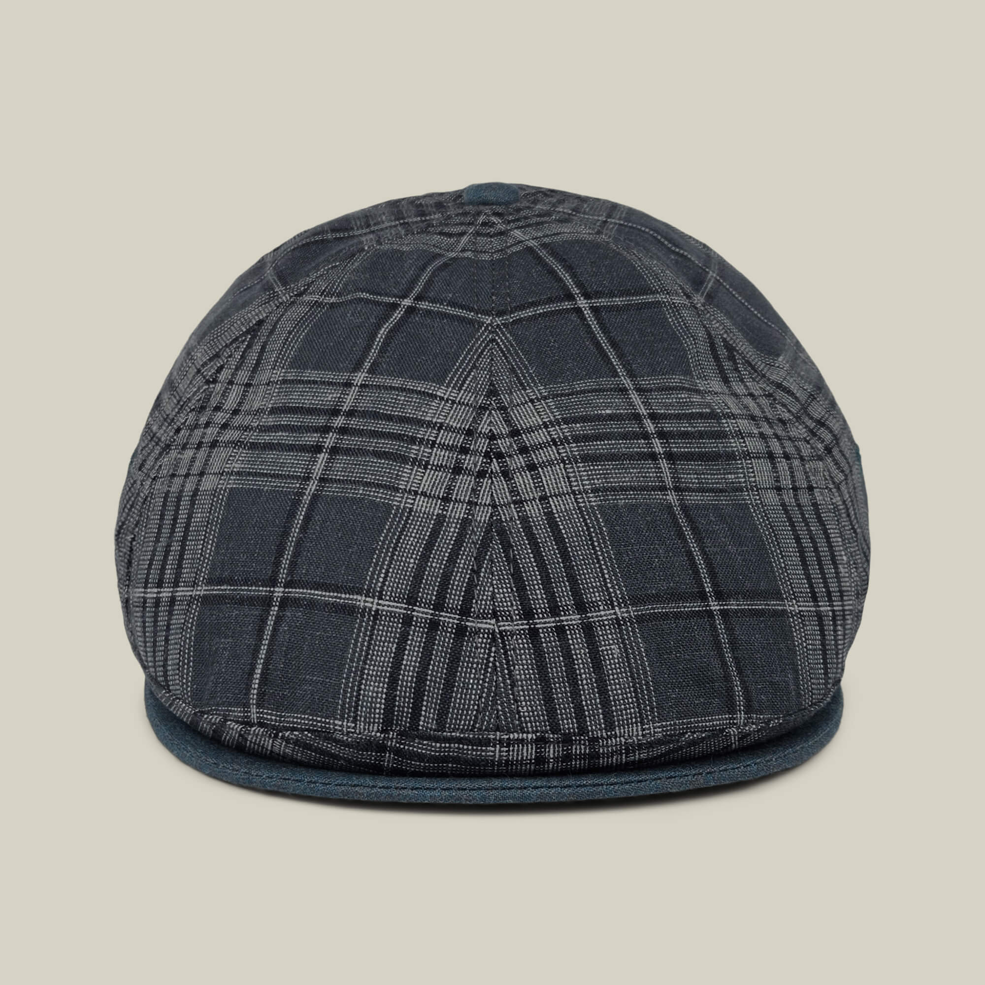 Front view of the Point Lobos 6 Panel Ivy flat cap by Goorin Bros., featuring a dark plaid design with a rounded crown and short brim, handmade in the USA from a breathable cotton blend, displayed against a plain beige background.