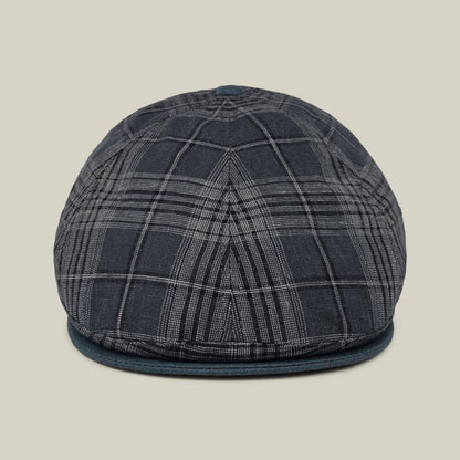 Front view of the Point Lobos 6 Panel Ivy flat cap by Goorin Bros., featuring a dark plaid design with a rounded crown and short brim, handmade in the USA from a breathable cotton blend, displayed against a plain beige background.
