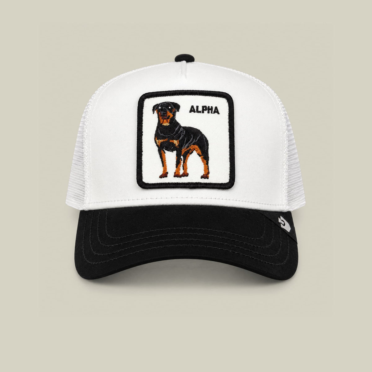The Goorin Bros. Suede Alpha trucker hat features a white mesh back, black suede bill, and embroidered rottweiler patch with "ALPHA" text on the white front panel, displayed against a neutral background.