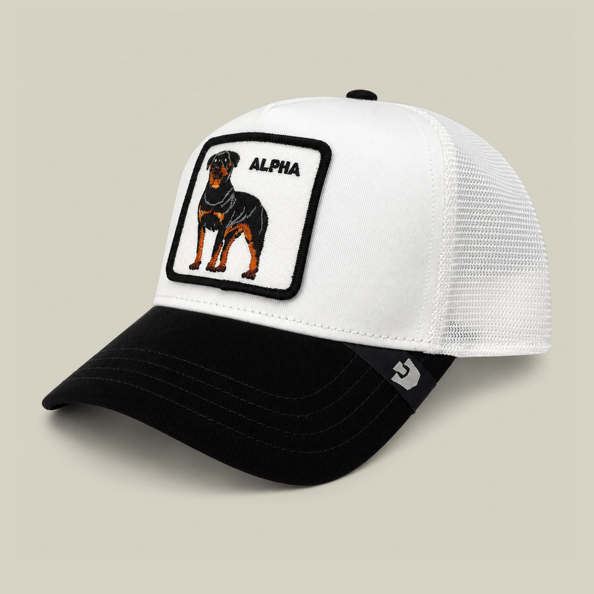 The Suede Alpha trucker hat by Goorin Bros features a white mesh back and black suede front with an embroidered rottweiler patch and alpha text on the crown, displayed on a neutral background.