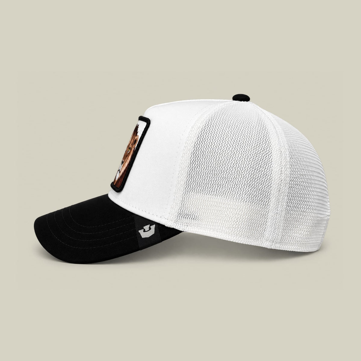 The Goorin Bros. Suede King trucker hat features a black suede bill and white mesh crown with a brown patch detail on the side, displayed in three-quarter view against a neutral beige background.