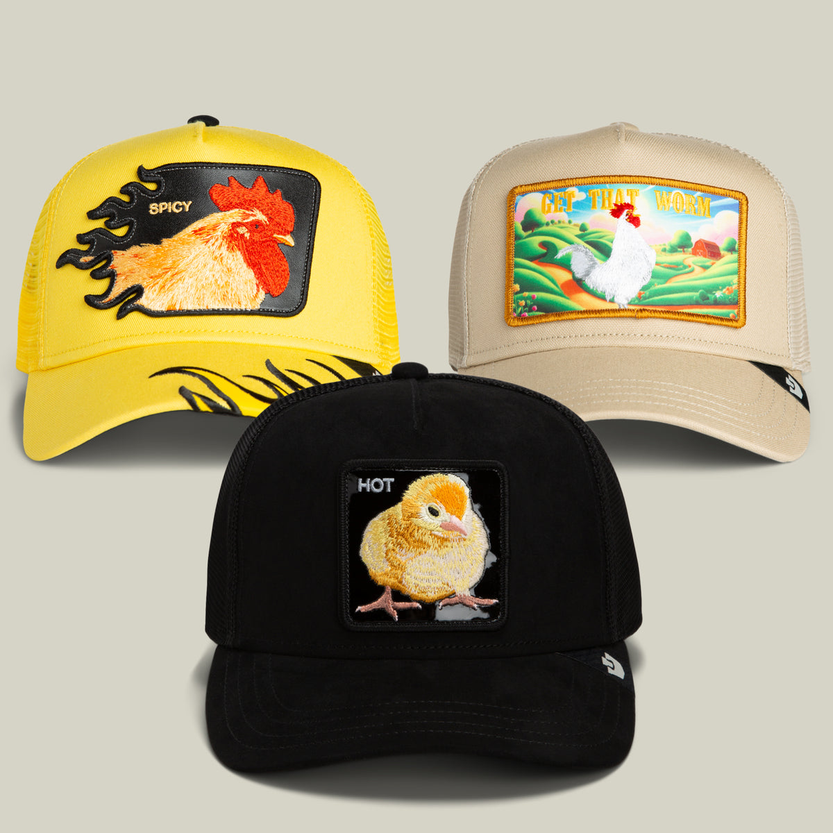 Discover the Colonel’s Choice Bundle from Goorin Bros.: a trio of distinctive trucker hats adorned with embroidered chicken designs. This exclusive set includes a yellow cap featuring a bold rooster, a tan hat showcasing a scenic landscape with a white chicken, and a black “Hot Chick” cap with charming chick embroidery. Each hat is presented against a plain backdrop.