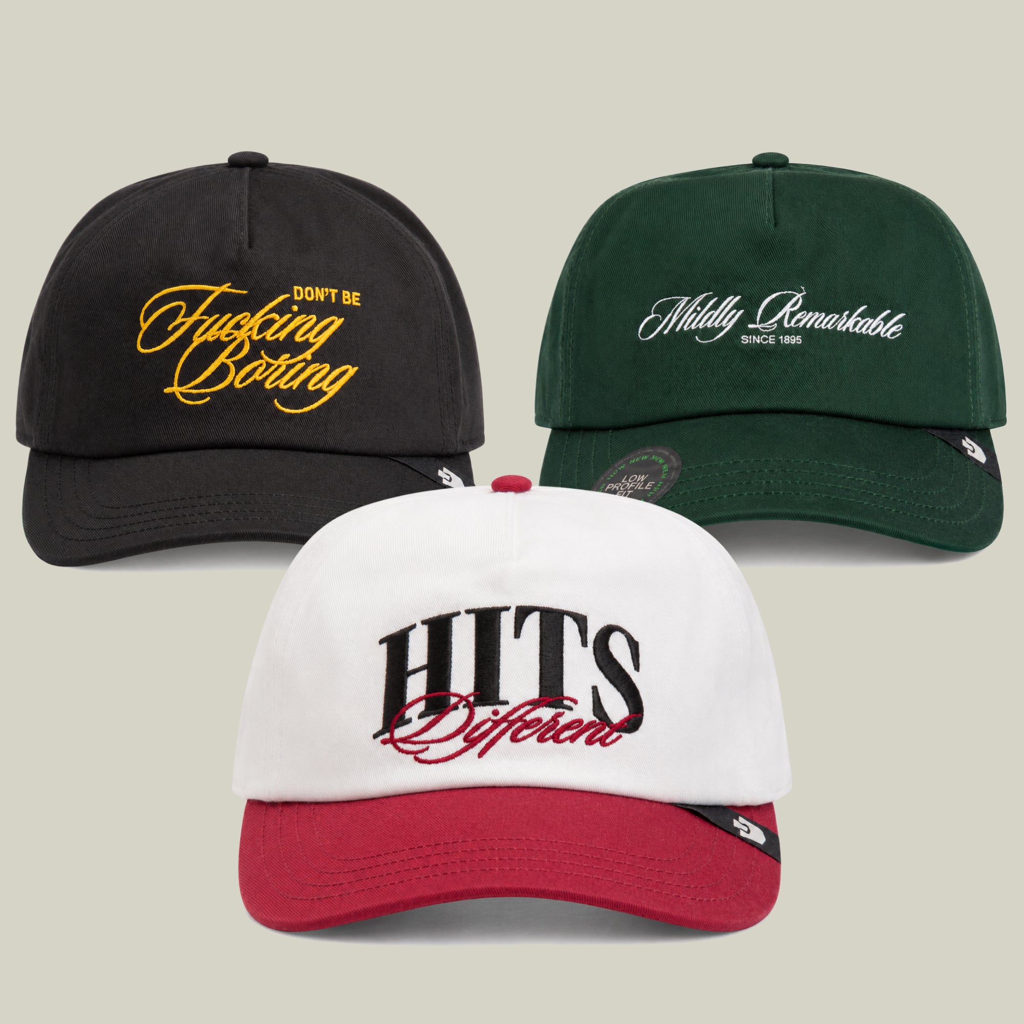 The Don’t Tell Me What To Do Bundle by Goorin Bros. features three baseball caps with embroidered text: a black cap boldly declaring Don’t Be Fucking Boring, a green cap that says Mildly Remarkable Since 1995, and a standout white and red HITS Different cap.