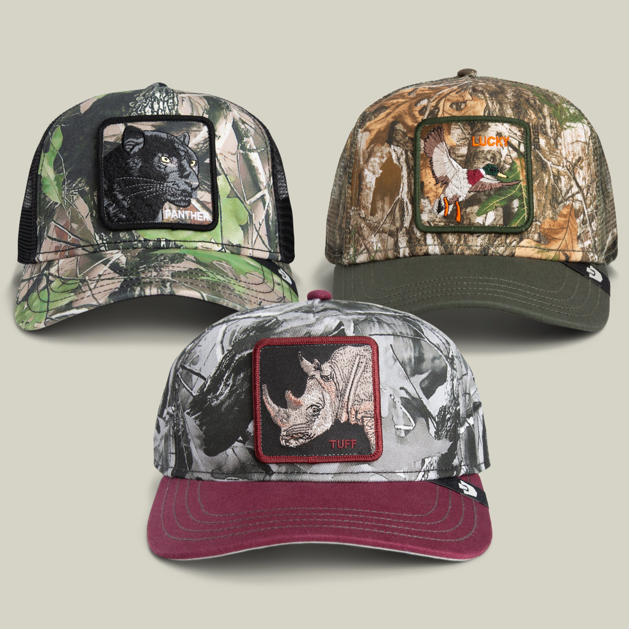 Three baseball caps from the Goorin Bros. Now You See Me Bundle, each showcasing a different camouflage pattern and a distinctive animal patch—panther, duck labeled LUCK, and rhinoceros labeled TUFF—are displayed against a light background.