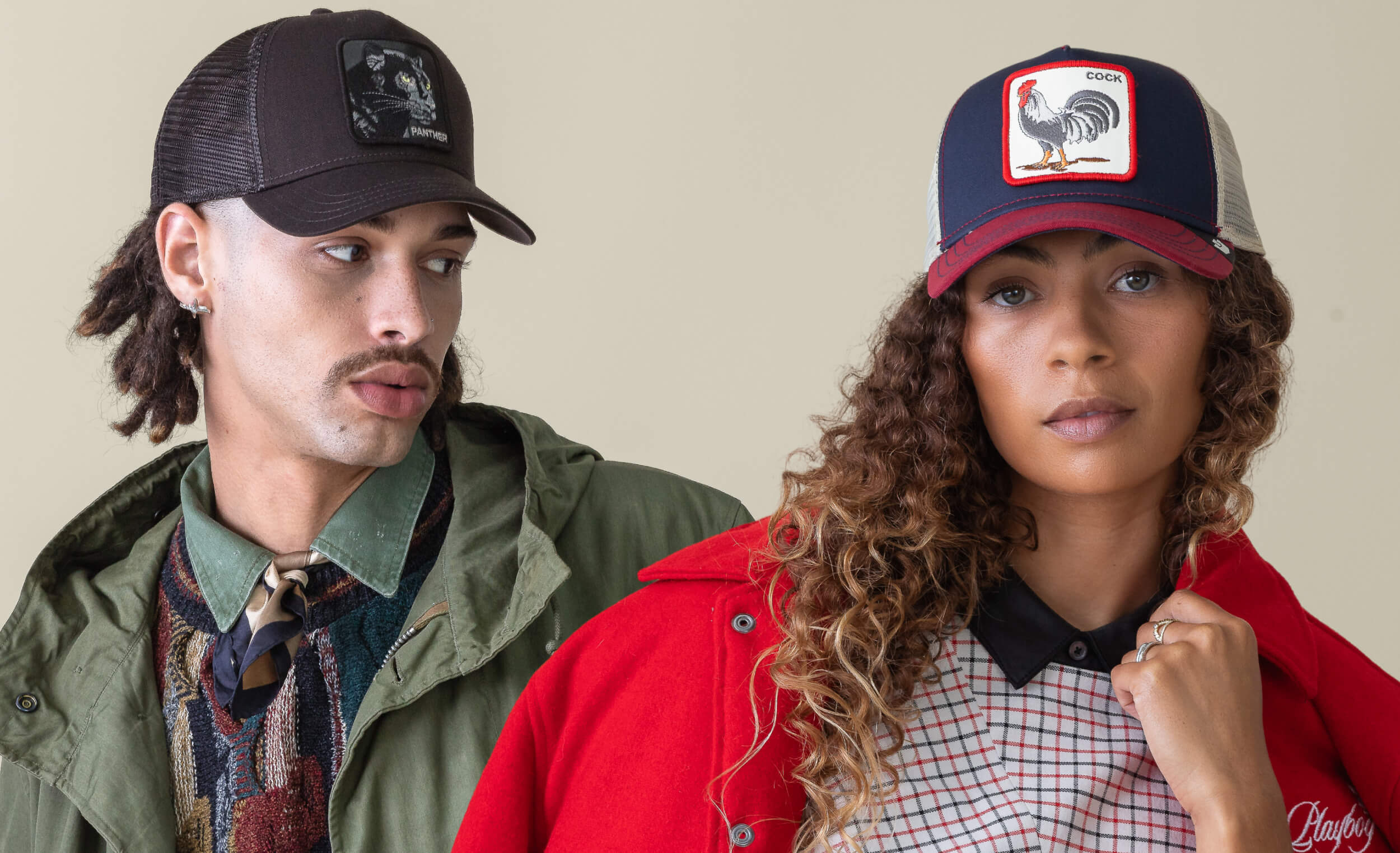 Two people wearing baseball caps with rooster designs against a plain background
