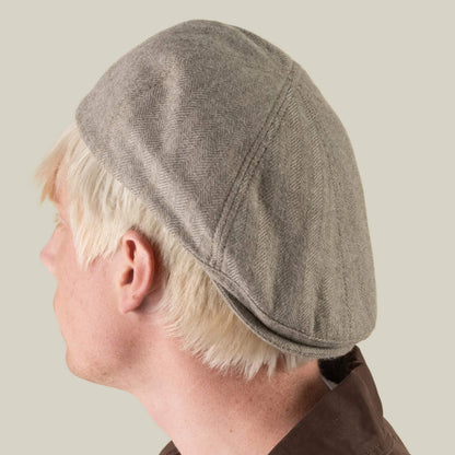 A person with short blond hair, seen from behind against a plain light background, wears the Goorin Bros. “Harry Bones” 100% wool gray flat cap and a brown collared shirt.
