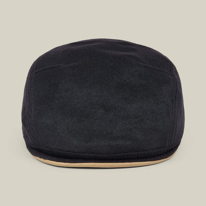 The Goorin Bros. Cornerstone is a black wool flat cap featuring a slightly curved brim and a beige accent along the edge, handmade in New Jersey and displayed against a plain light background.