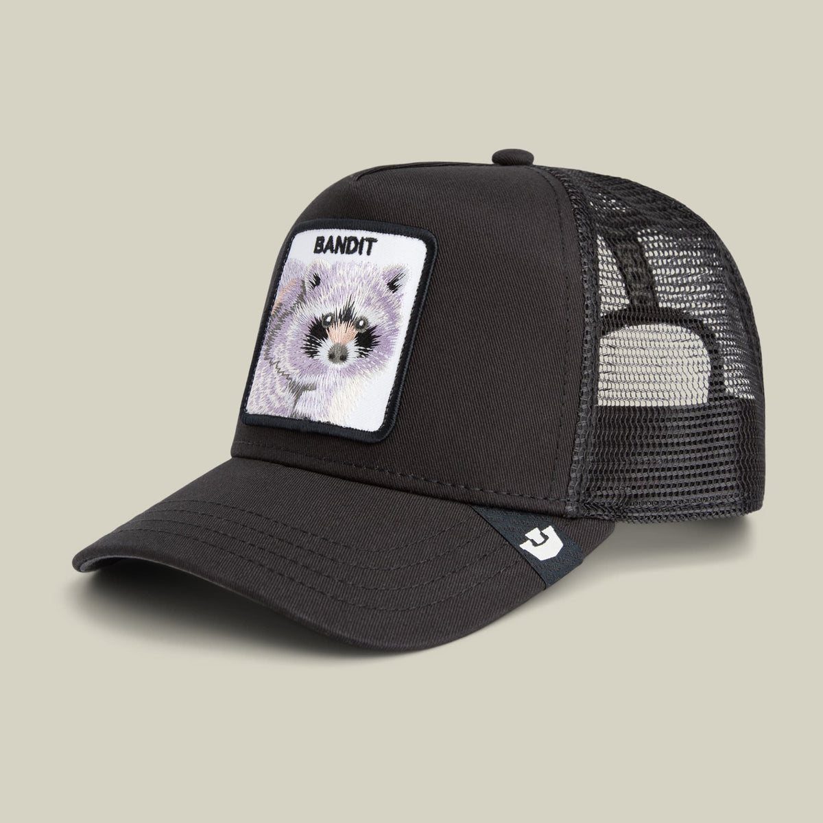 The Goorin Bros. Bandit Trucker is a black mesh trucker hat with a front patch featuring a detailed raccoon illustration and "Bandit" text, shown against a neutral studio background.