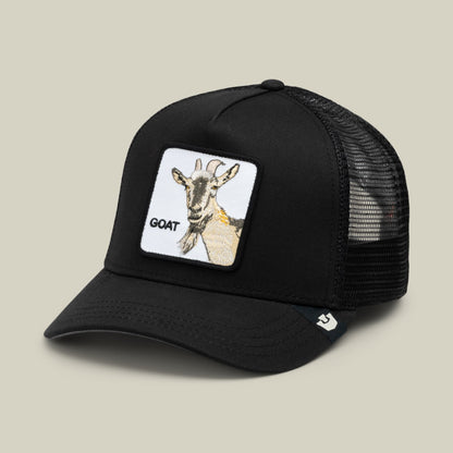 The Goorin Bros. Goat Beard black trucker hat features a mesh back, curved brim, and white patch with a beige goat illustration and "GOAT" text on the front.