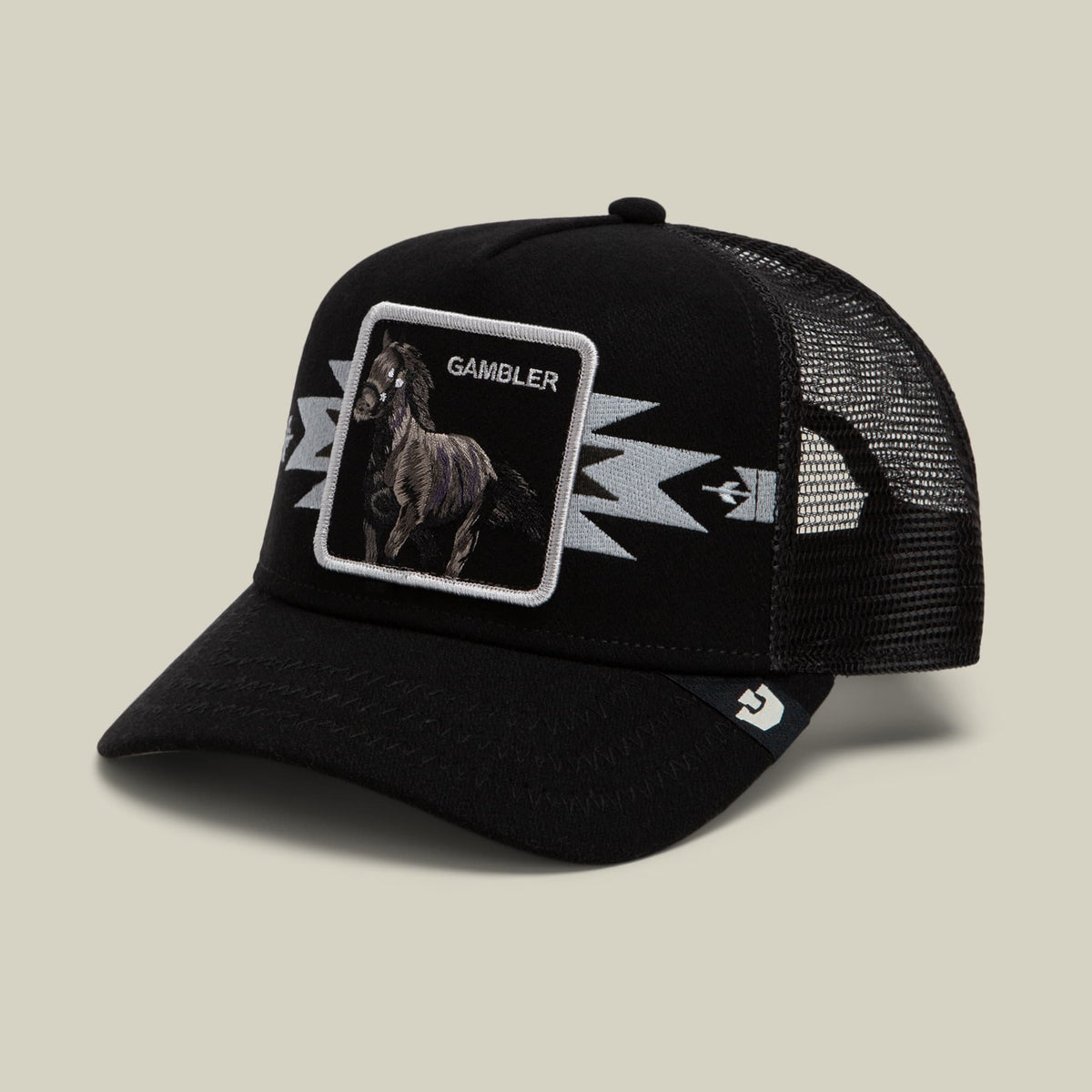 The Canyon Gambler by Goorin Bros is a black trucker hat with a mesh back, featuring an embroidered rooster patch labeled "Gambler" and white lightning bolt designs on the front.